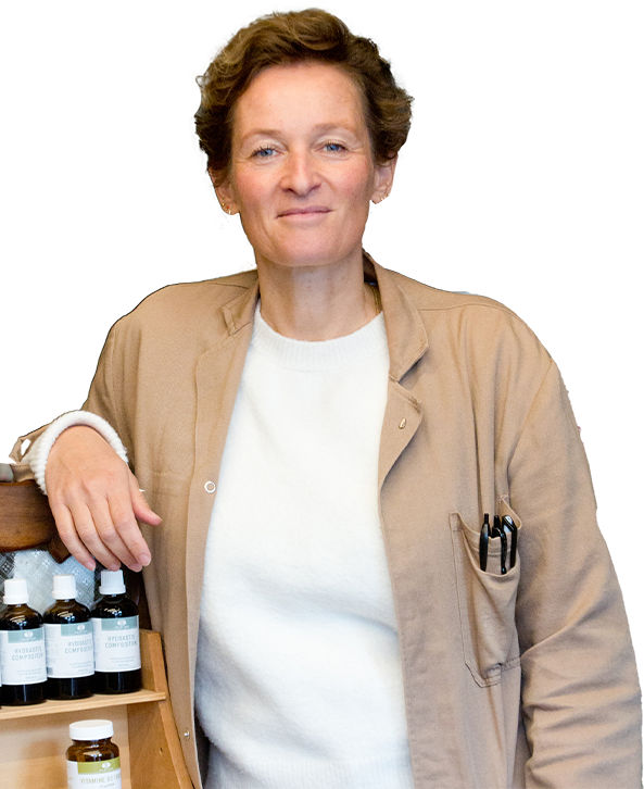 Lachende Petra Vlieger in de winkel met bruine stofjas