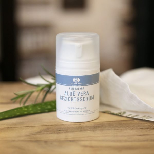 Aloë vera gezichtsserum witte pompflacon Huidbalanslijn op houten ondergrond met doek en aloe vera stengel