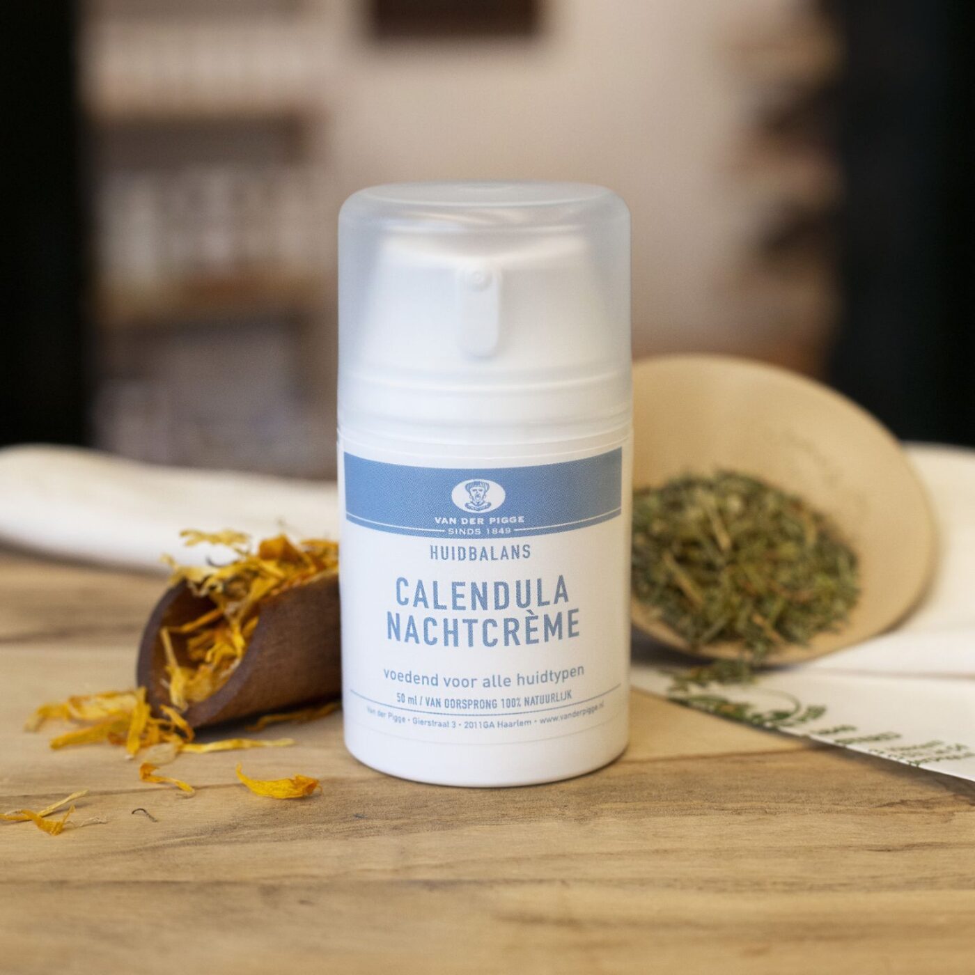 Witte plastic pompflacon Calendula nachtcrème 50 ml op houten ondergrond met decoratieve kruiden en puntzak