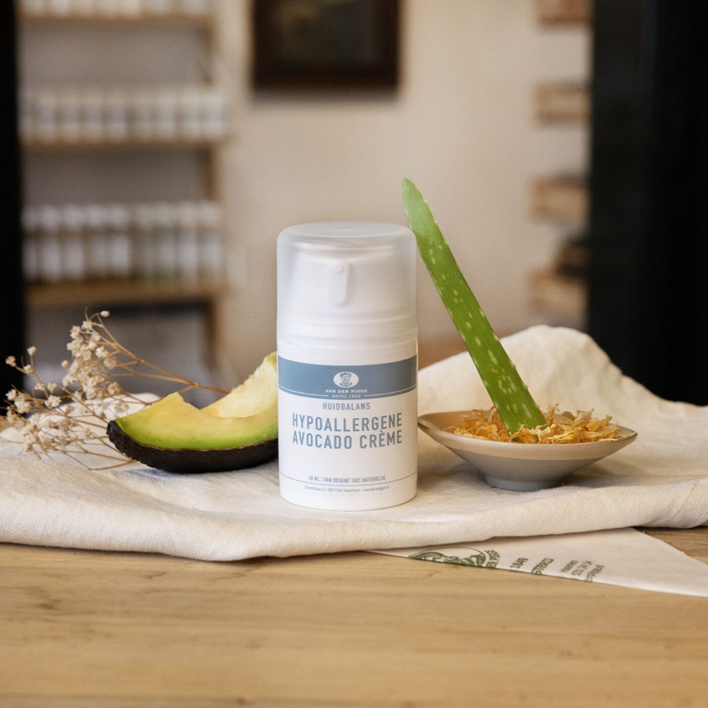 Plastic pompflacon wit met hypoallergene avocadocrème Huidbalans op houten toonbank met witte doek en decoratieve kruiden en avocado