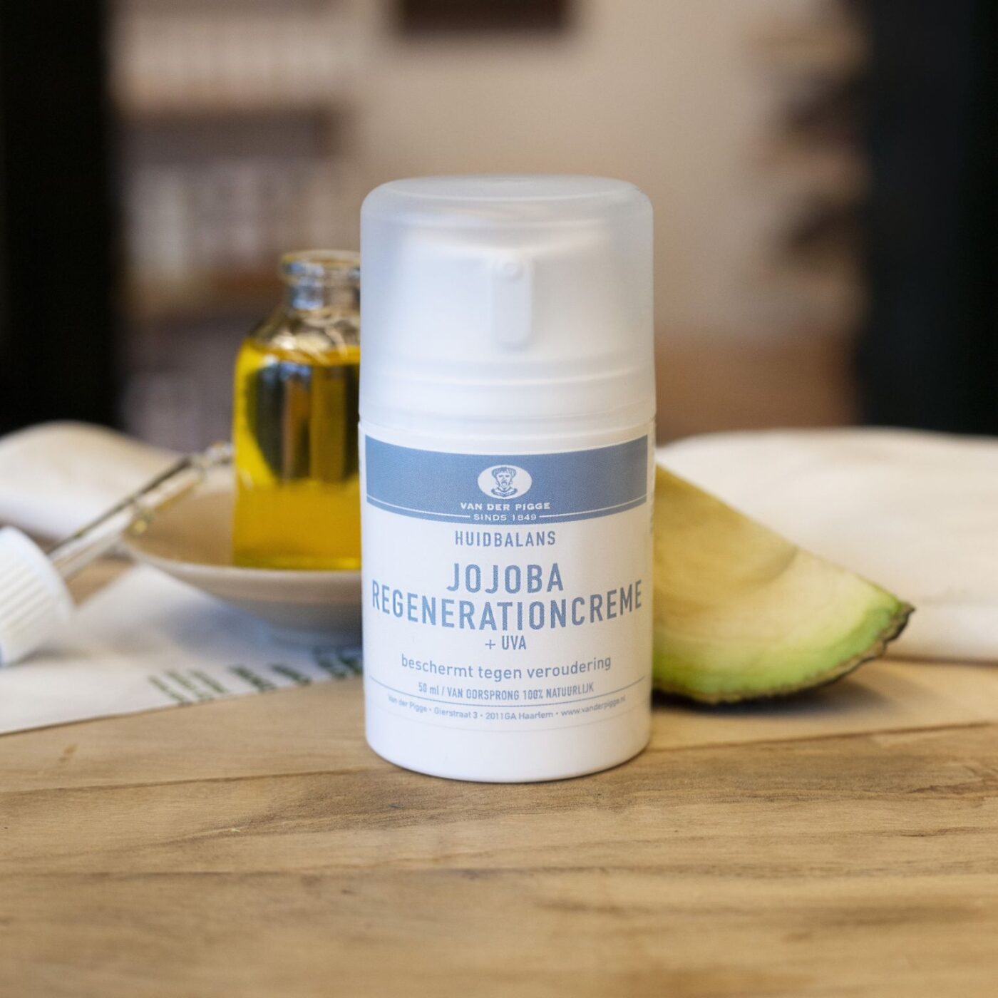 Plastic witte pompflacon 50 ml jojoba regenerationcrème huidbalans op houten toonbank met decoratieve kruiden
