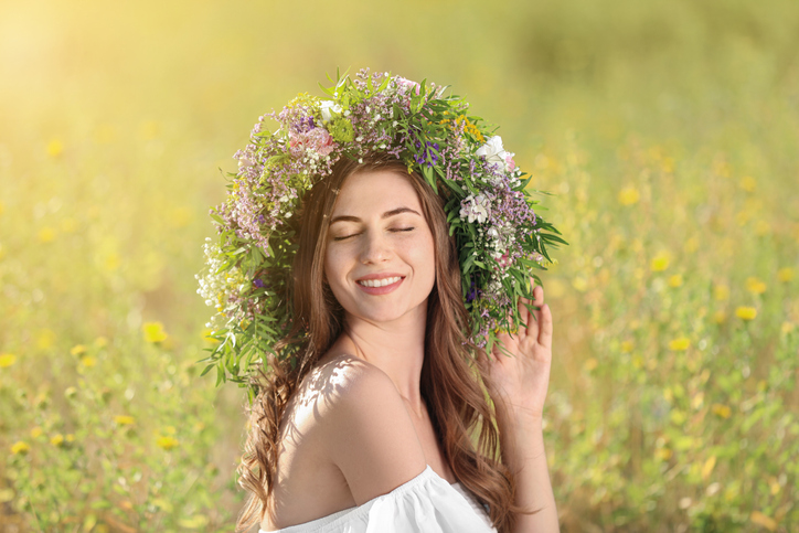 beltane vruchtbaarheidsfeest Jonge vrouw met een krans gemaakt van prachtige bloemen in het veld op zonnige dag