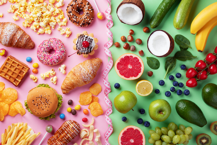 Gezonde en ongezonde voedingsachtergrond van fruit en groenten versus fastfood, snoep en gebak bovenaanzicht. Dieet en detox tegen calorie- en overgewicht levensstijlconcept gescheiden met meetlint. inflammaging gezonde en ongezonde voeding
