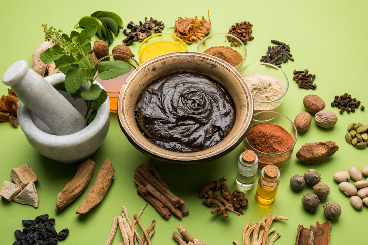 ayurveda kruiden en specerijen en een vijzel; groene achtergrond