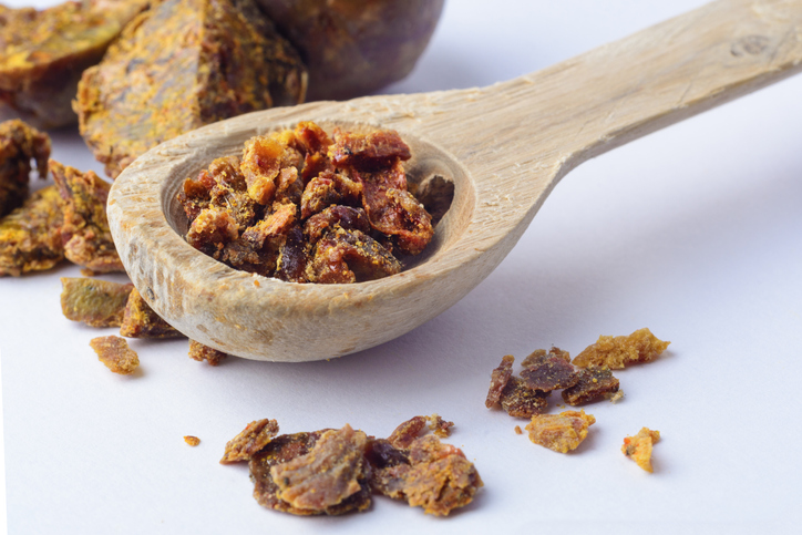 Een houten lepel vol bruine brokjes Propolis